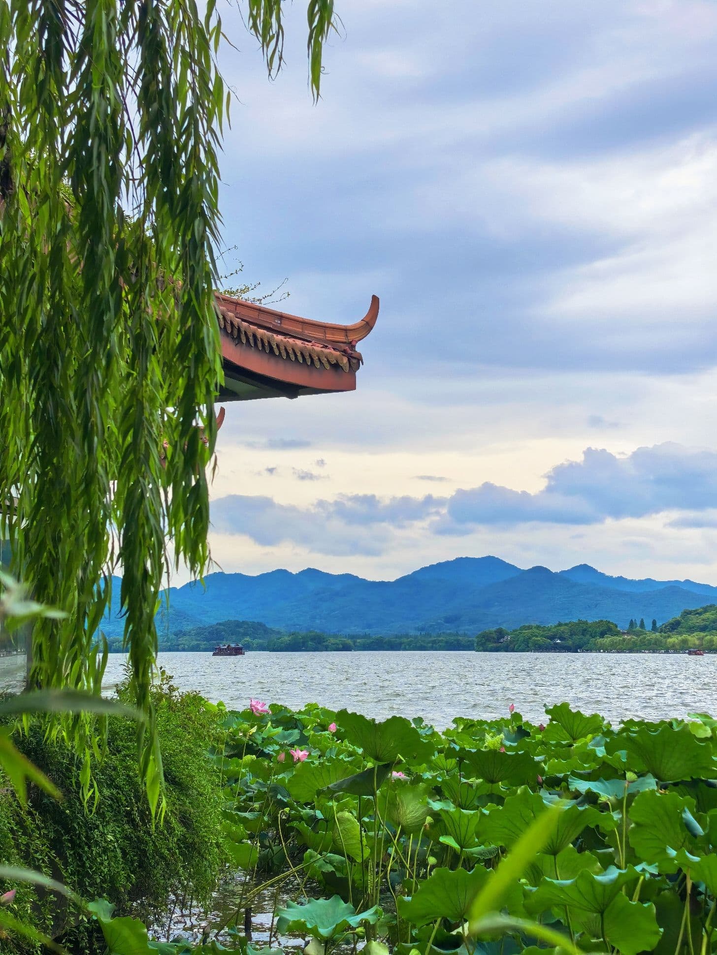 Lotus leaves, willow branches, pavilion roof, and mountains at West Lake in Hangzhou