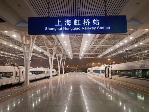 High-speed trains beside a Shanghai Hongqiao Railway Station platform sign